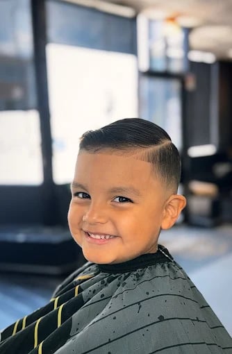 Smiling young boy in barber cape after getting a fresh haircut