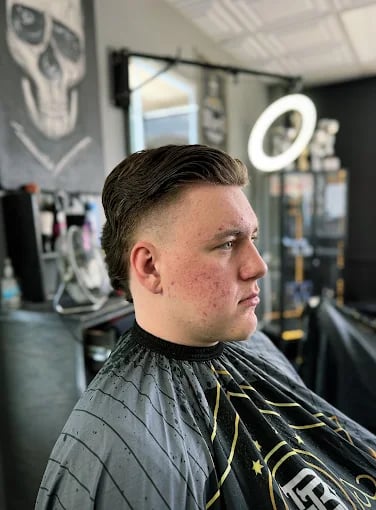 Man getting haircut in barbershop with skull artwork in background