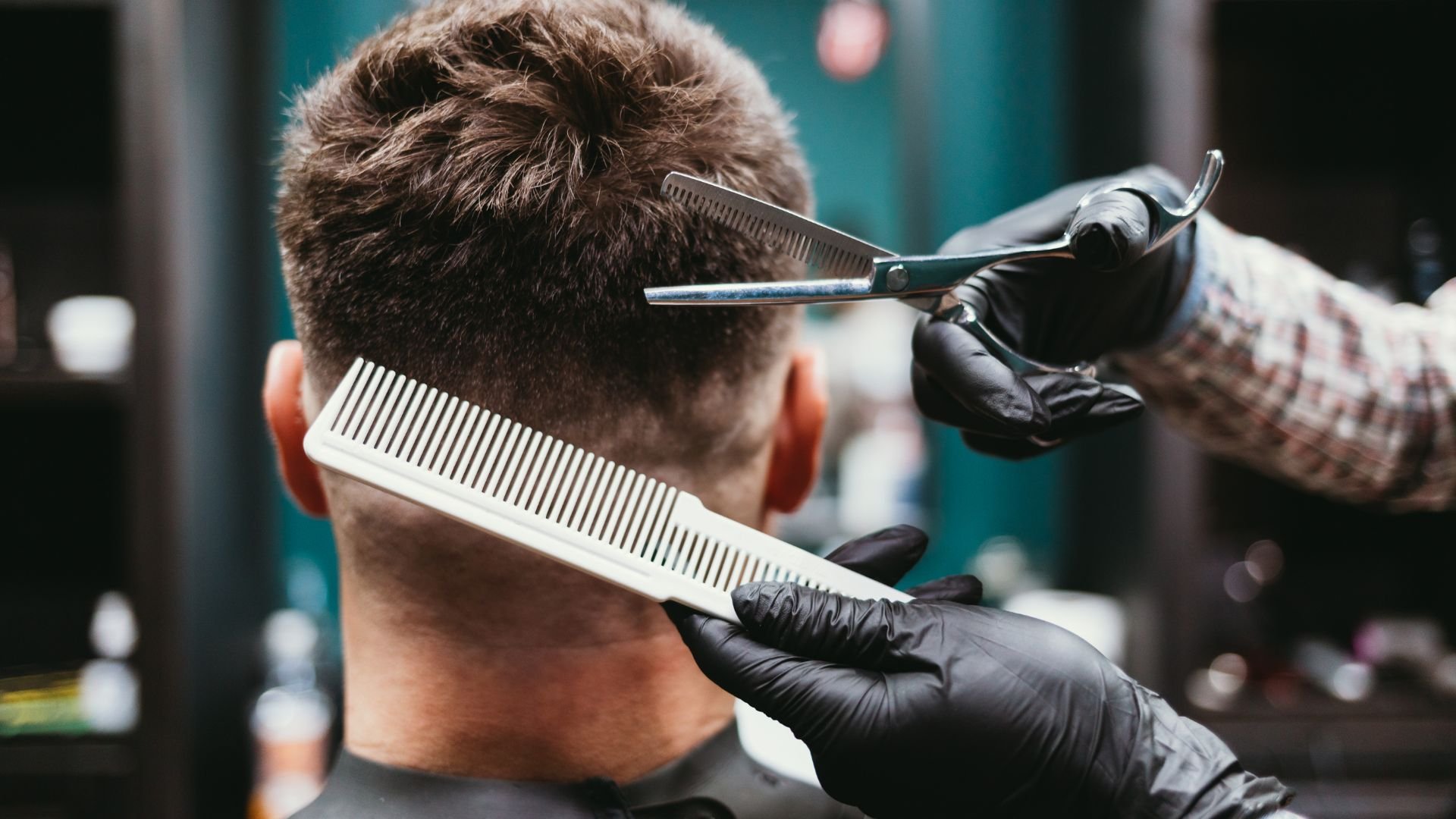 Barber cutting hair with scissors and comb in professional salon