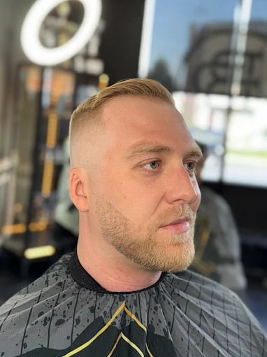 Man with short hair and beard in barber shop, side profile