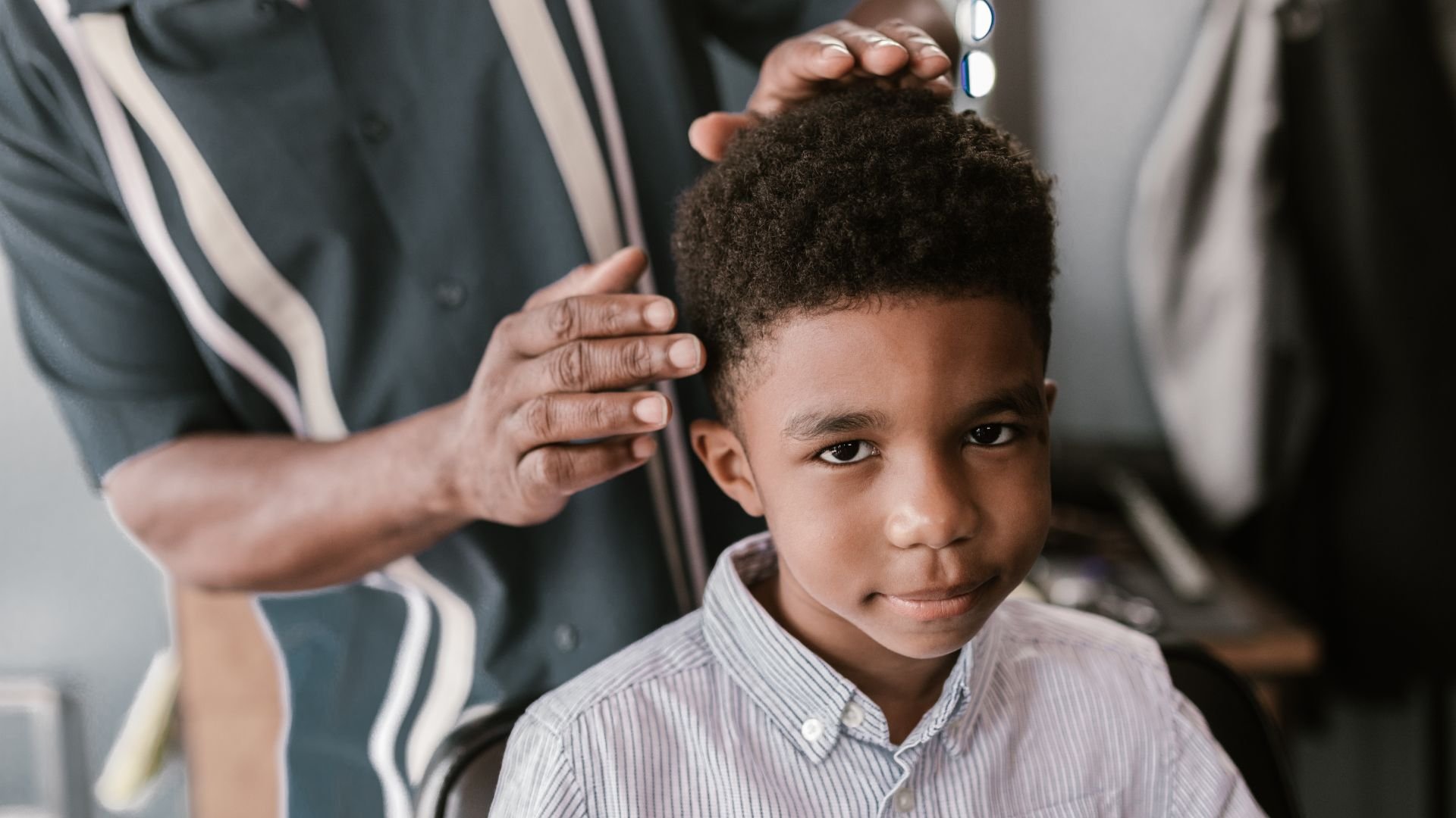 Child getting a haircut, hairdresser's hand on his head